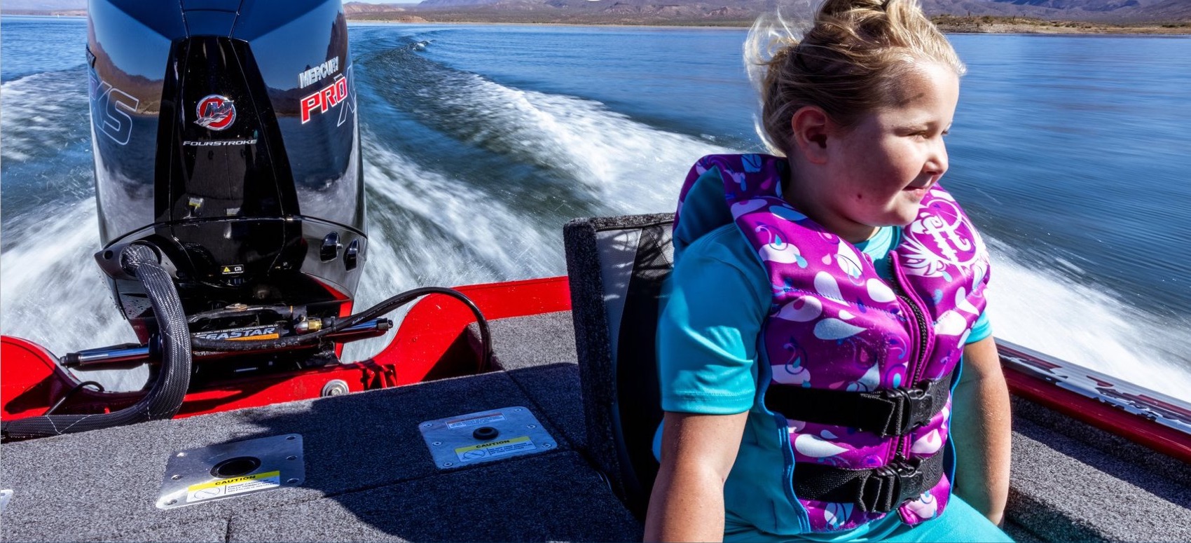 Girl in a life jacket riding in a bass boat